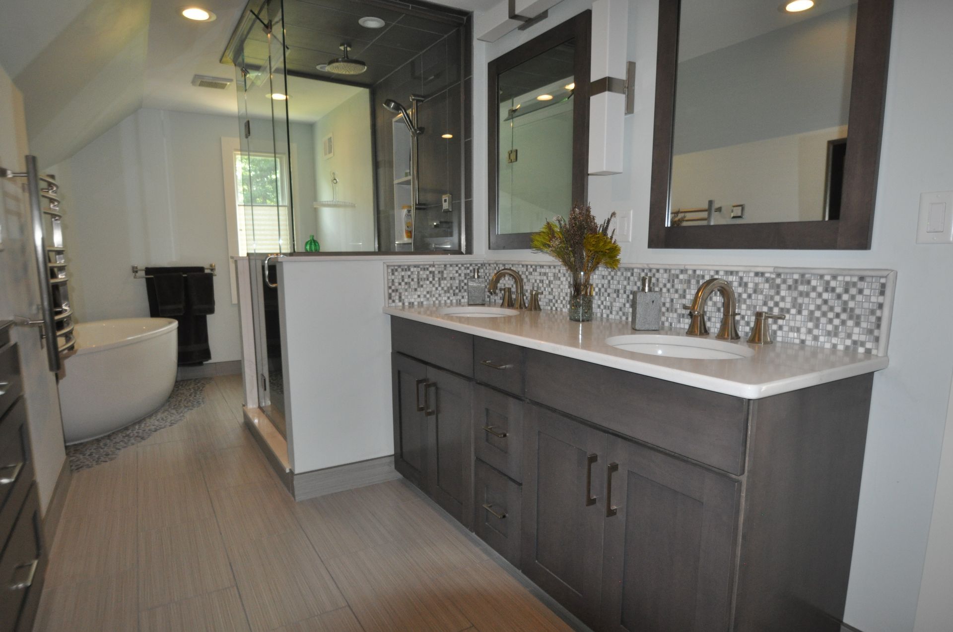 Modern bathroom with double vanity, walk-in shower, and freestanding tub. Grey cabinetry, marble countertops.