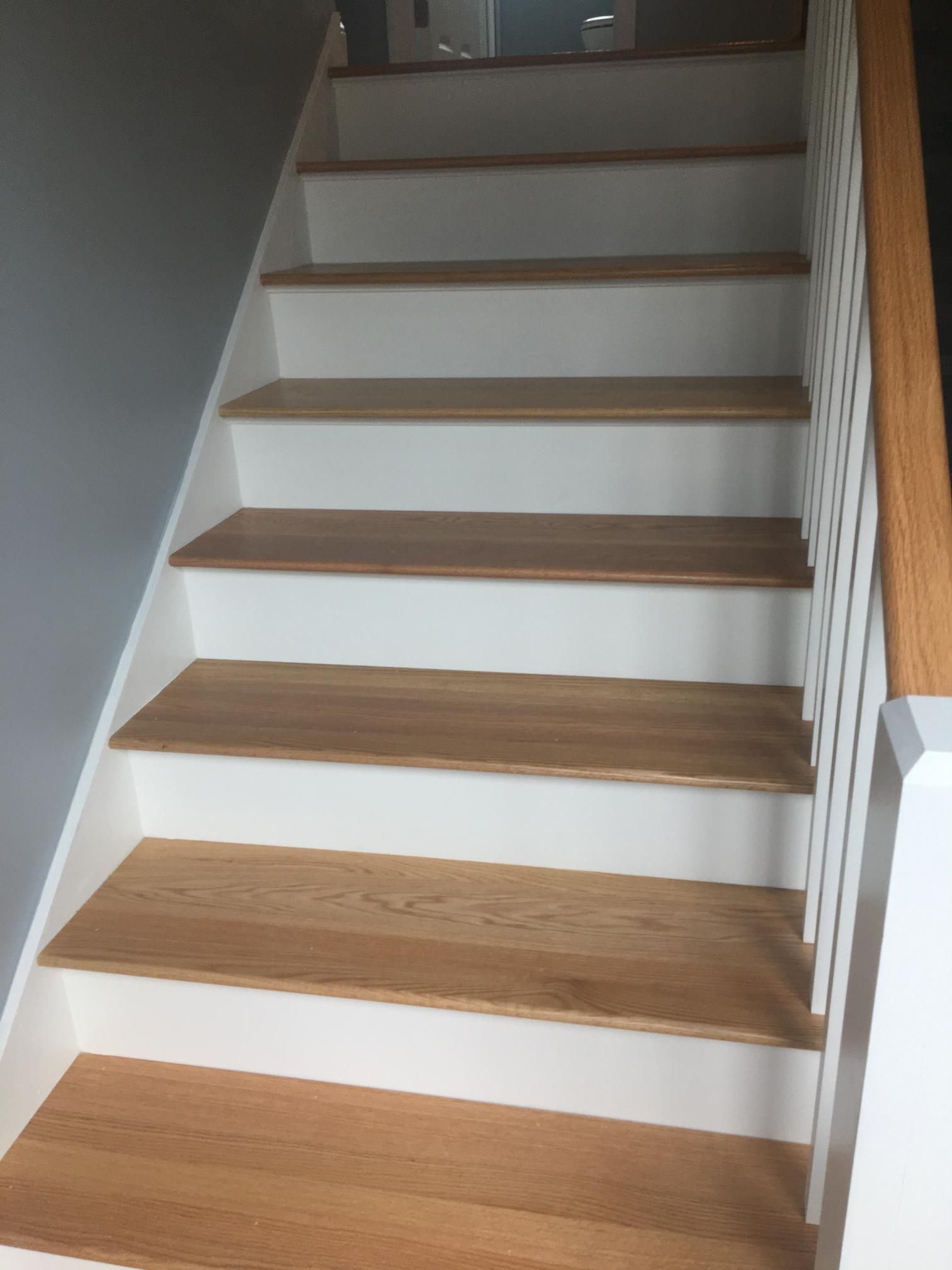 Staircase with light wood treads, white risers, and a white railing with wood handrail.