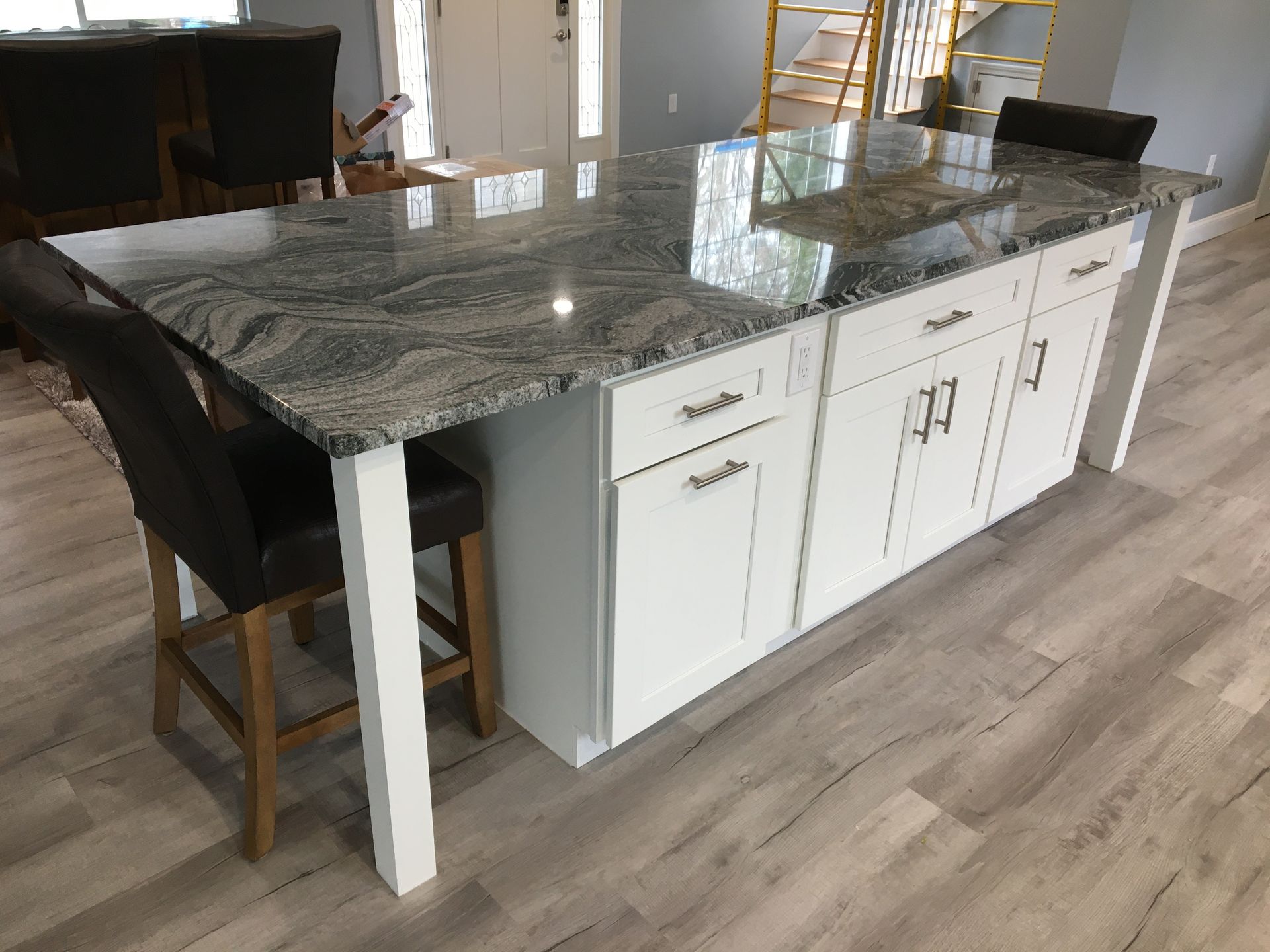 Kitchen island with white cabinets, granite countertop, and seating.
