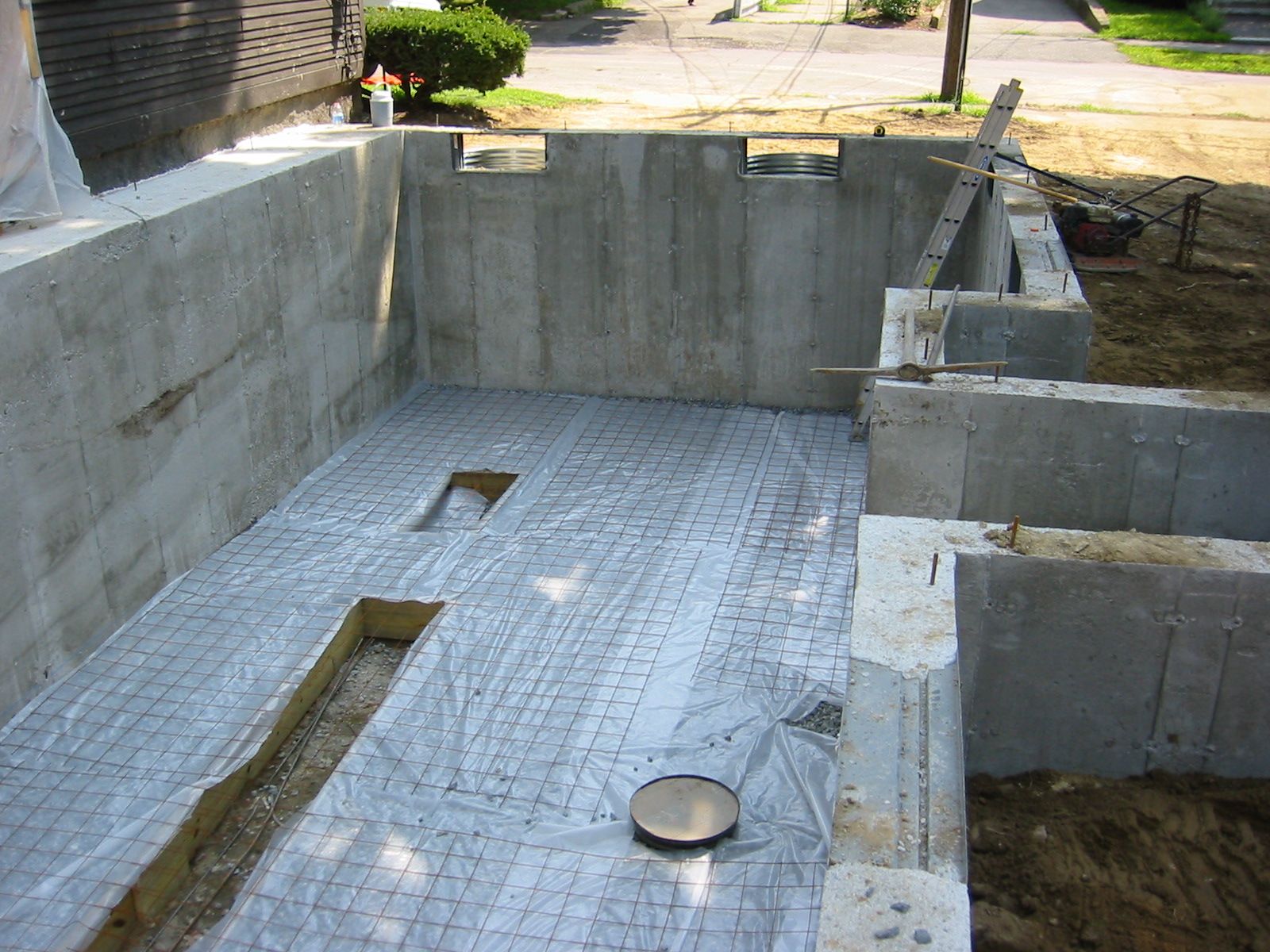 Concrete foundation under construction, with rebar, a gray color, and a partial view of the street.