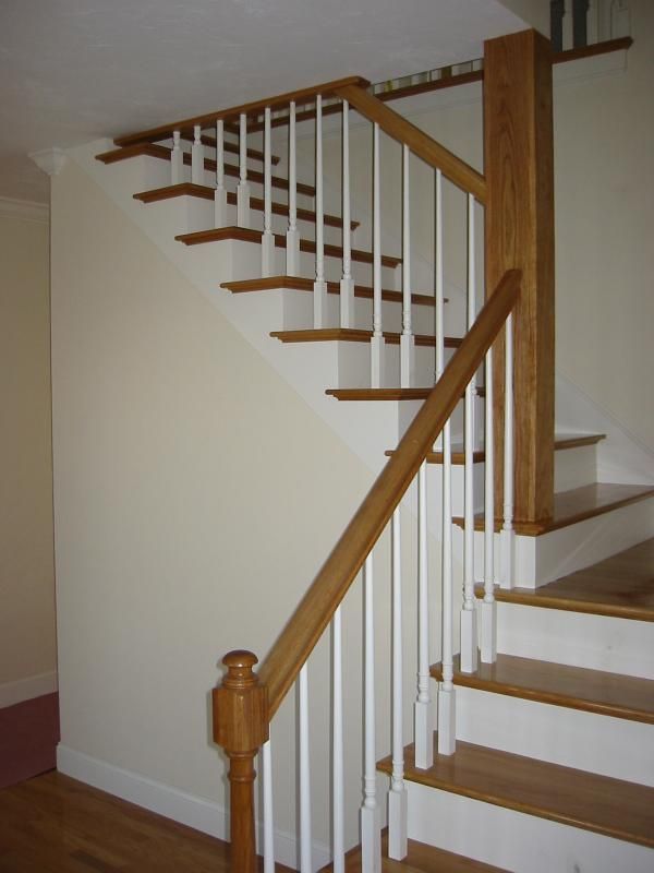 Staircase with wooden steps and railing, white spindles, and a wooden newel post.