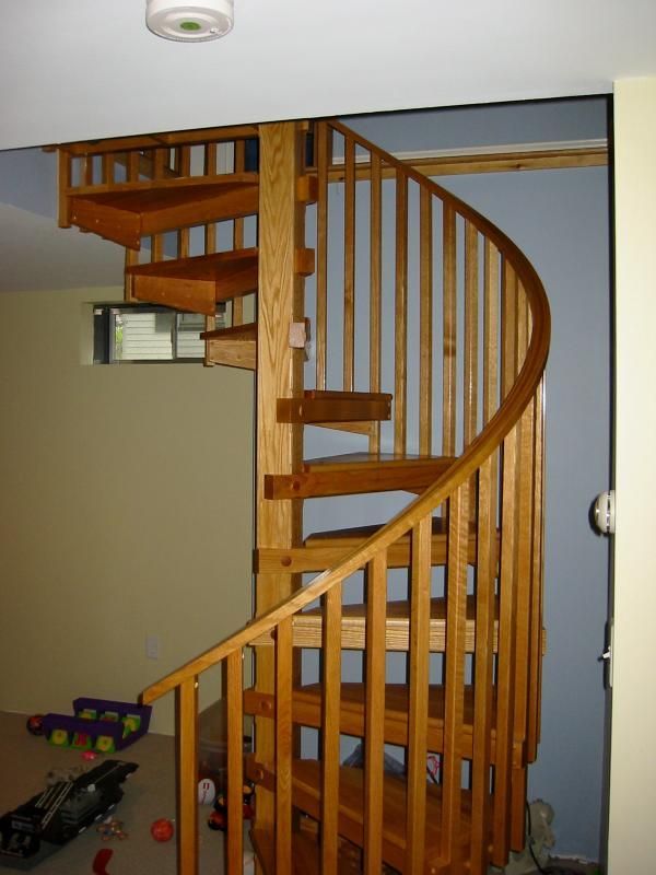 Wooden spiral staircase in a house. Banister, steps, and railing are all made of wood.