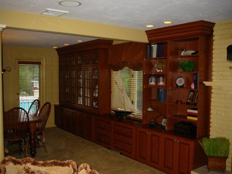 Wooden built-in cabinetry with bookshelves, a mirrored window, and a dining room visible on the left.