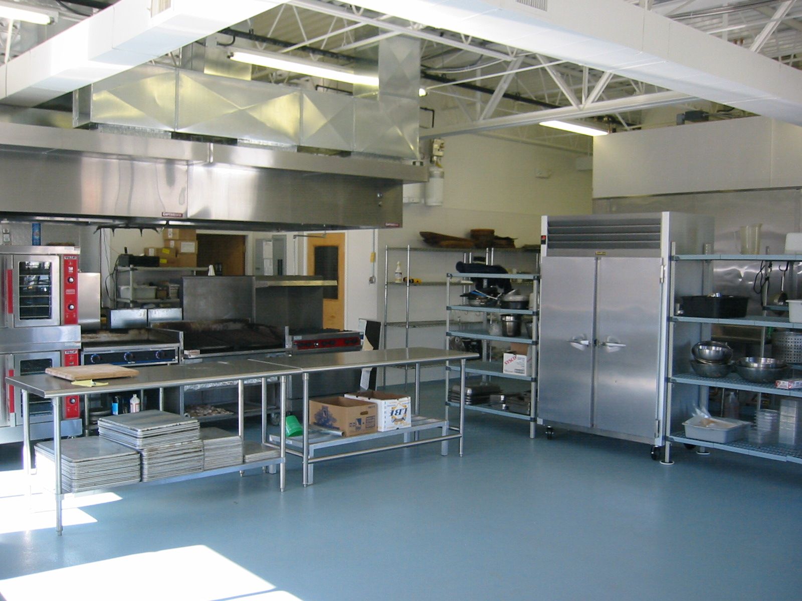 Commercial kitchen with stainless steel appliances and blue floor.
