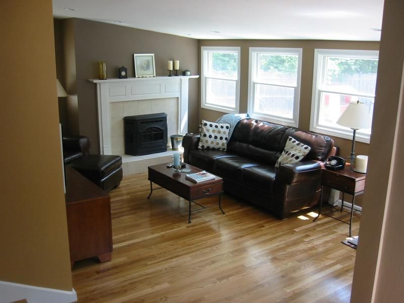 Living room with brown walls, fireplace, leather couch, and wooden floor.
