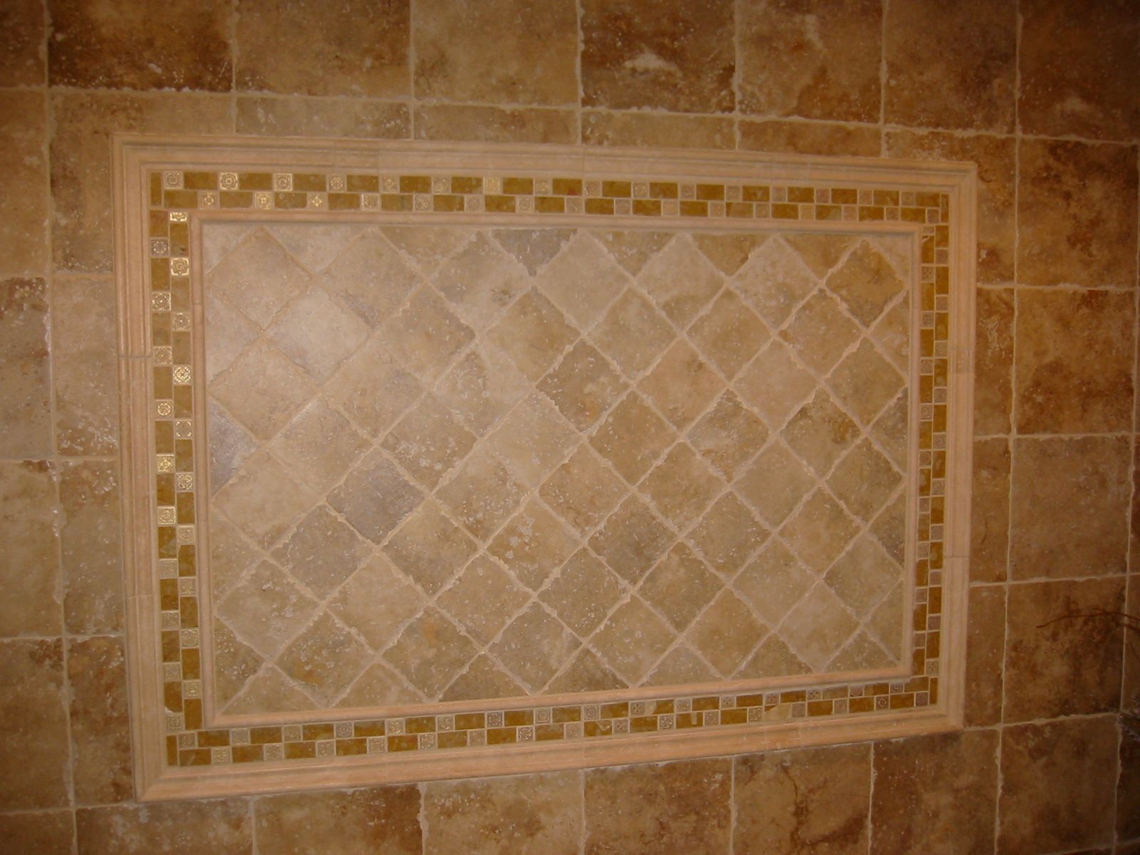 Brown tiled wall with a decorative diamond-patterned inset framed by gold mosaic tiles.