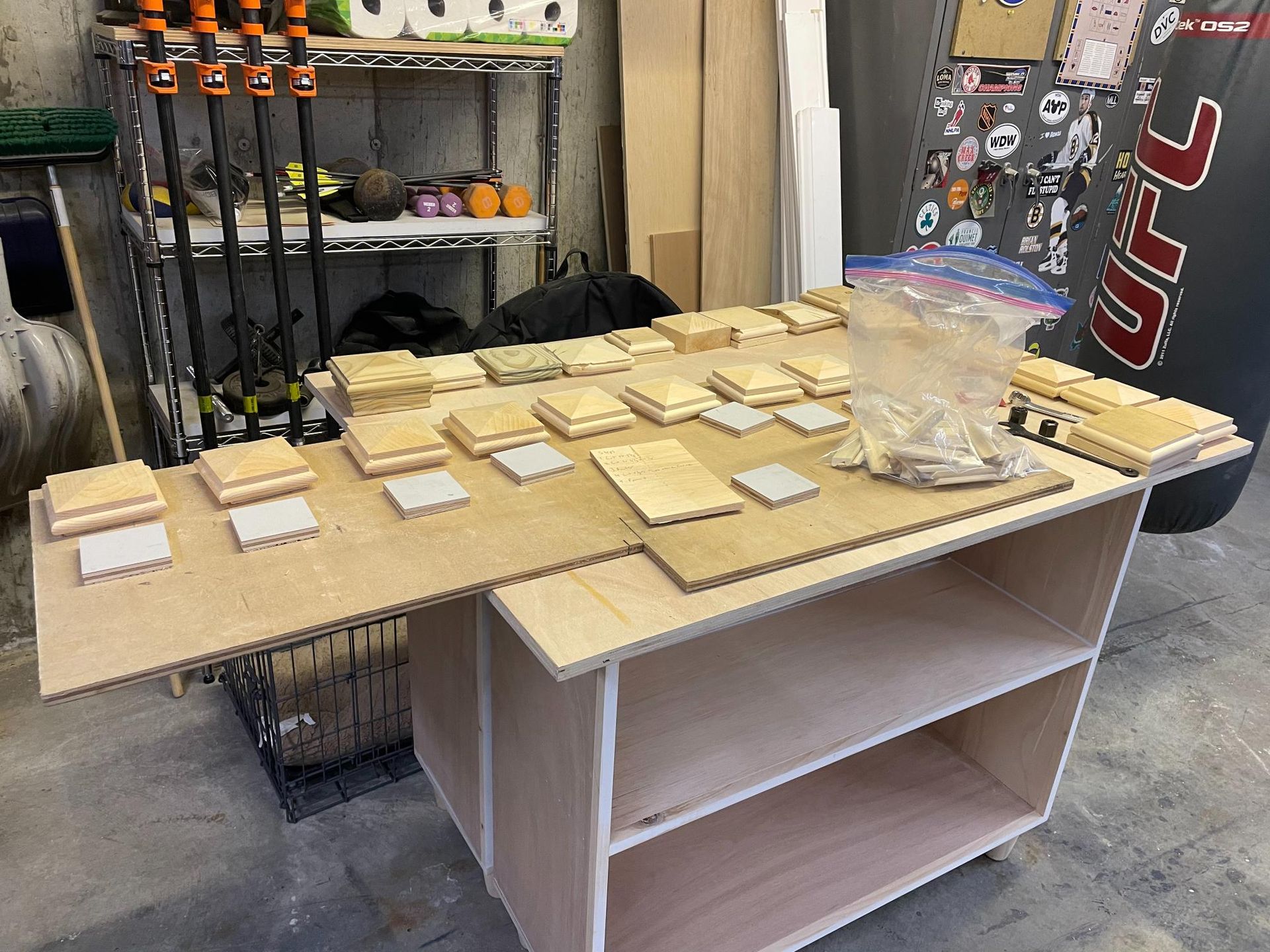 Wooden pieces arranged on a plywood sheet on top of a partially constructed cabinet in a workshop.