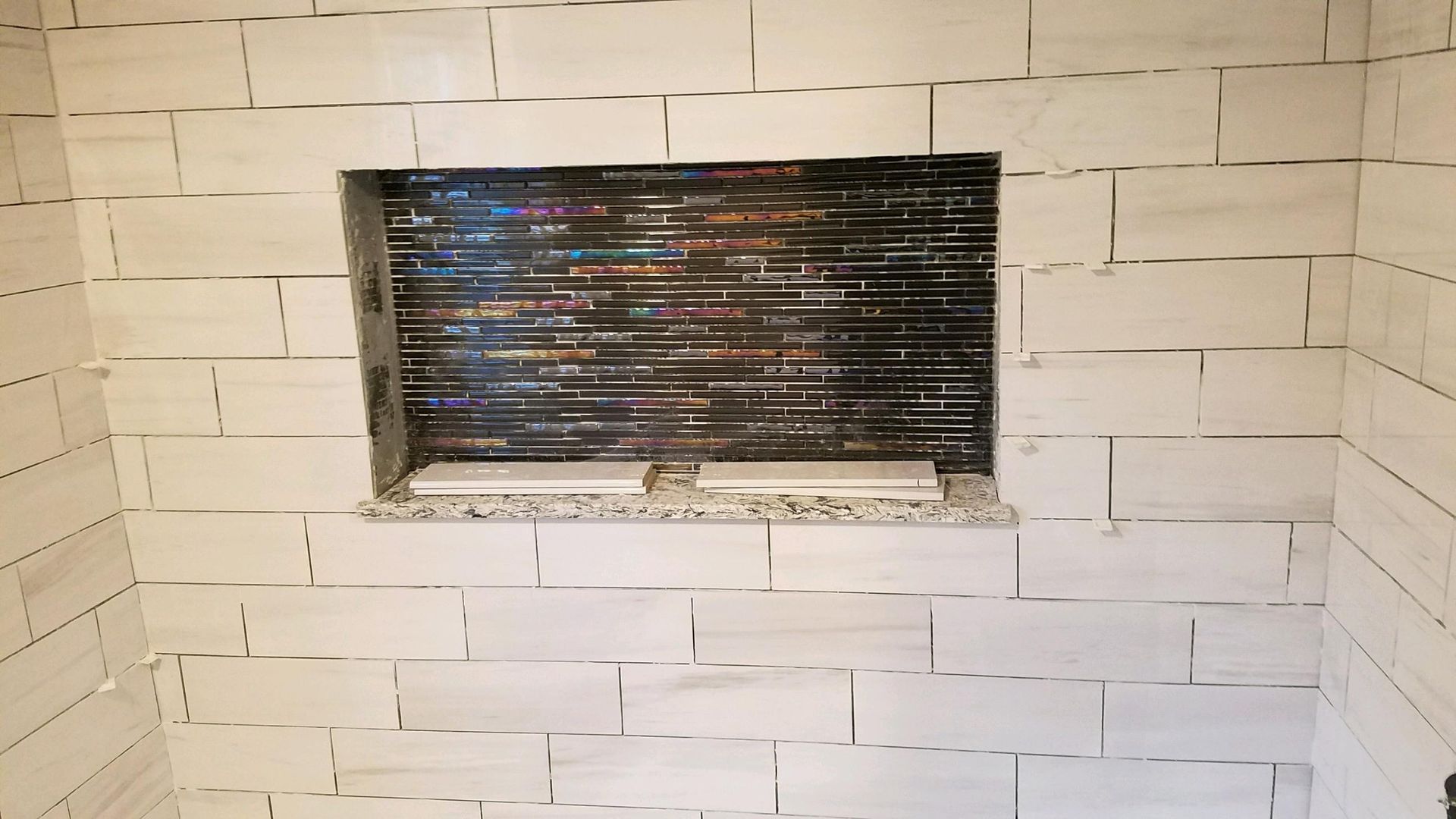Shower wall with a tiled niche, the back wall is a mosaic.