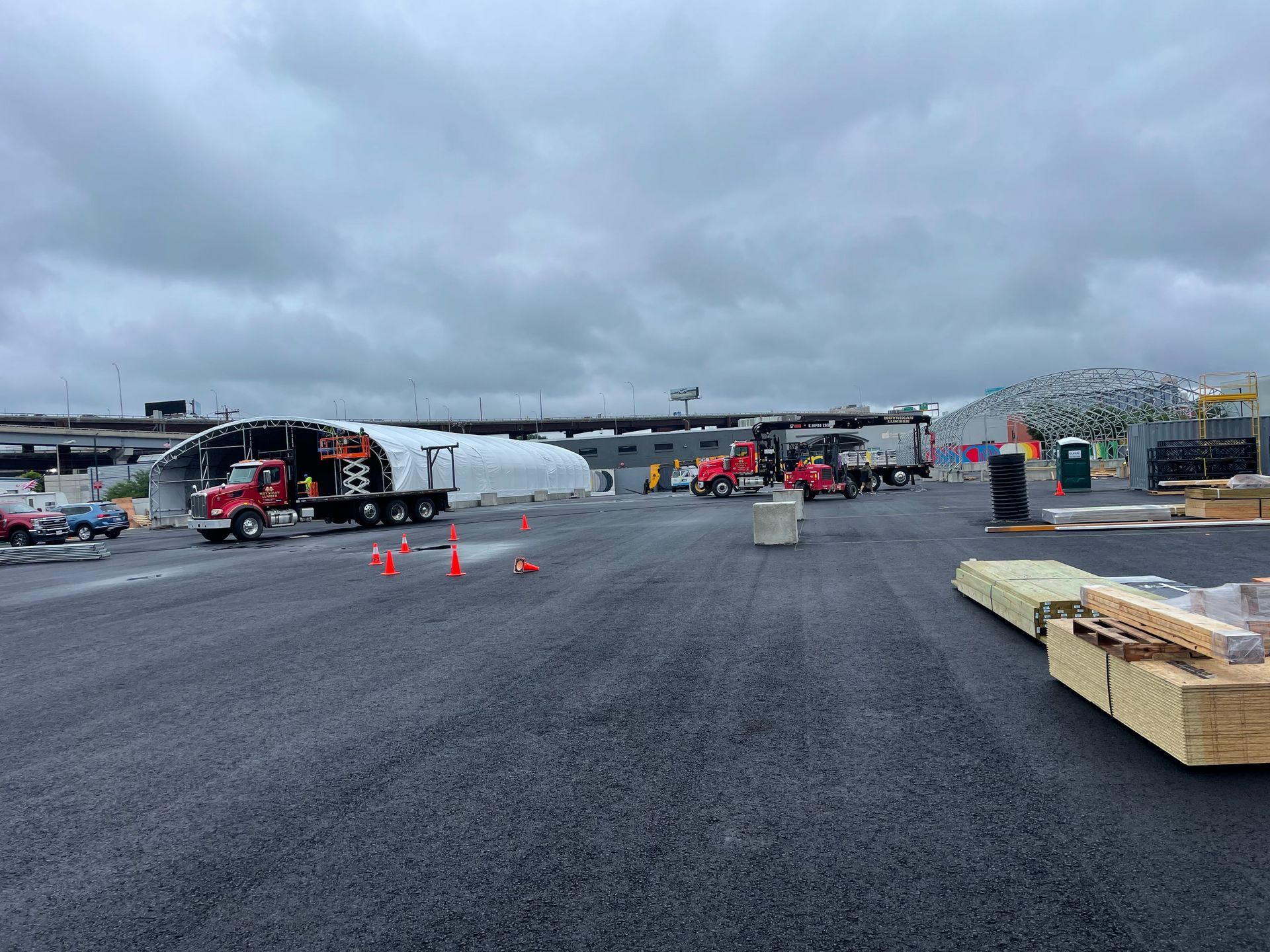 Construction site with trucks, storage, and temporary structures under a cloudy sky.