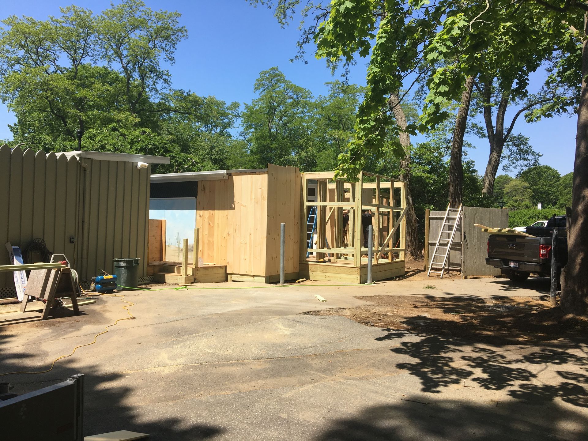 Construction site with partially built wooden structures, outdoor setting, clear blue sky.