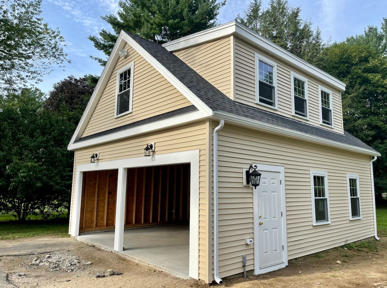 Two-story tan and beige garage with two bays, windows, and white trim.