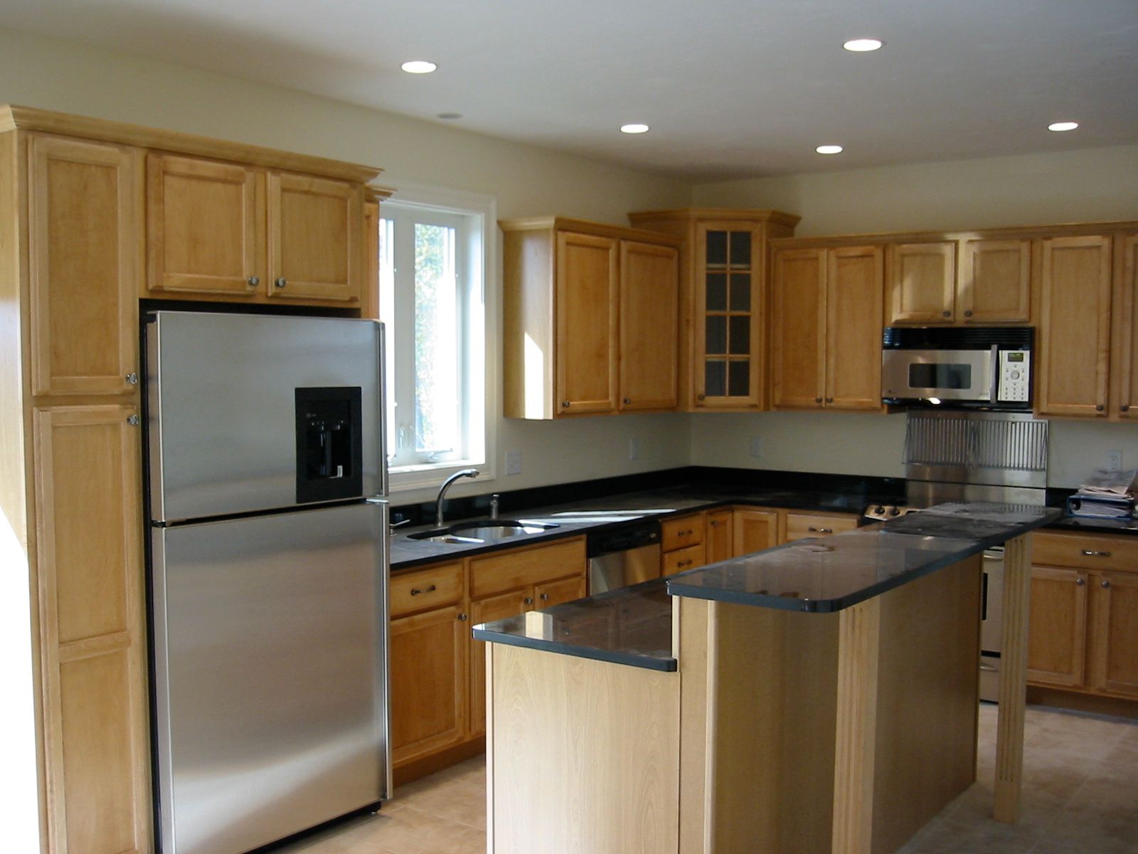 Light wood kitchen with stainless steel appliances, dark countertops, and an island.