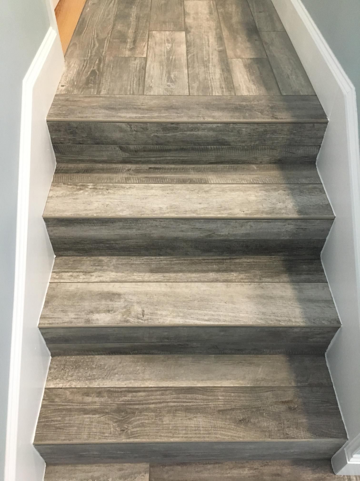 Staircase with wood-look gray flooring; white trim outlines the steps and walls.
