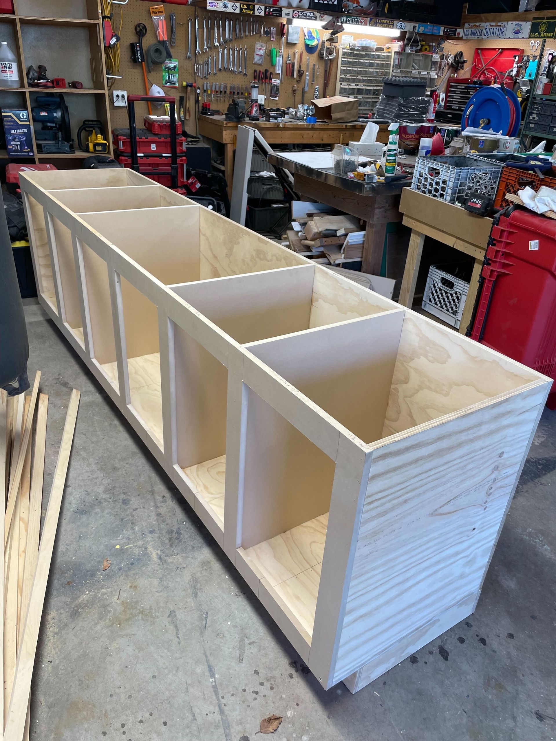 Wooden storage unit with multiple open compartments in a workshop.