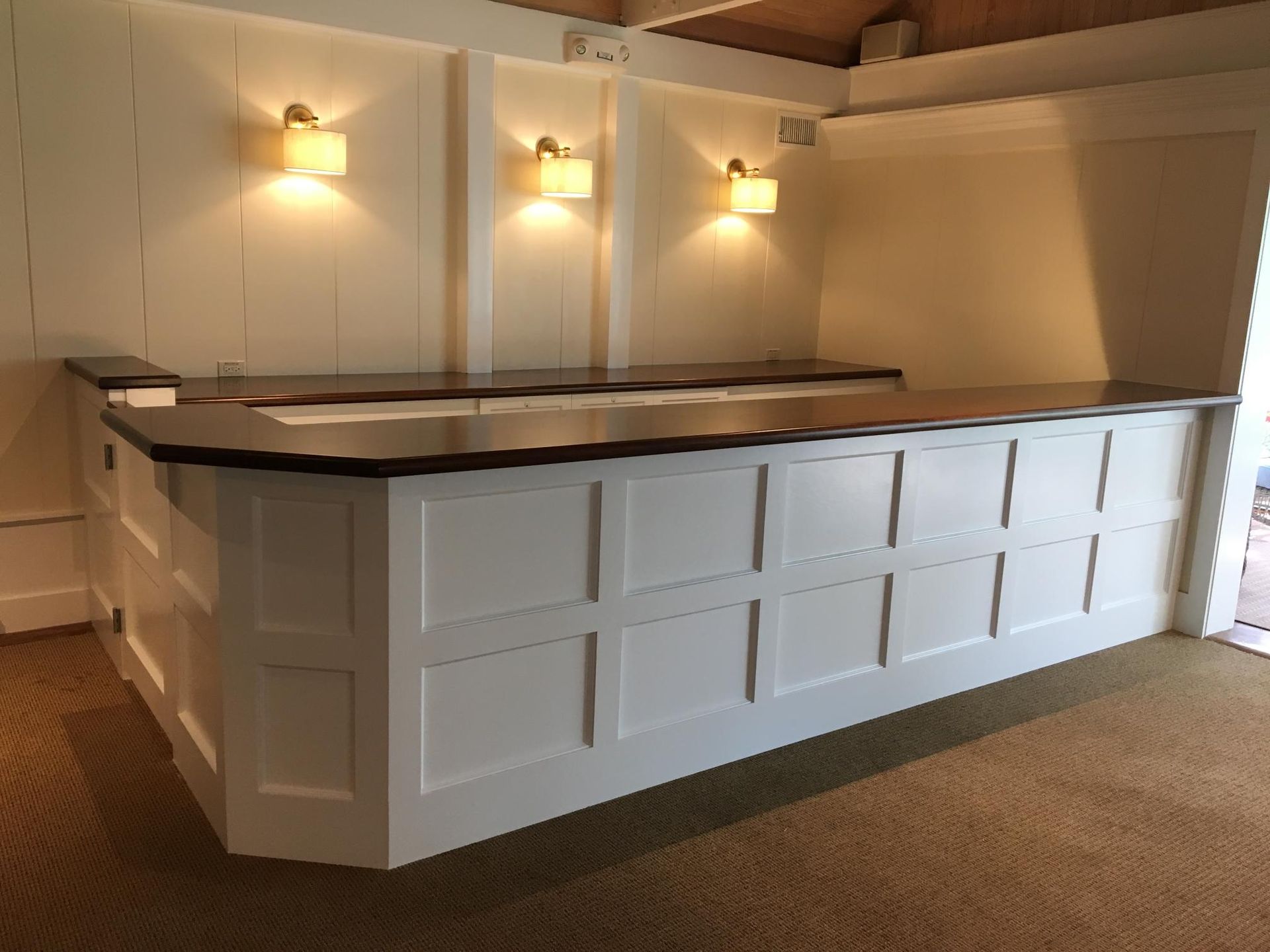 White bar with black countertop and sconce lighting.