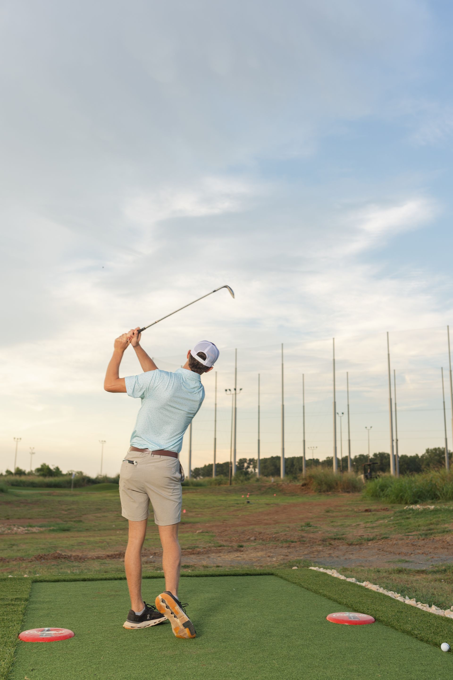 A man is jumping in the air while holding a golf club on a golf course.