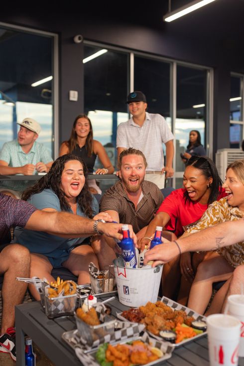 A group of people are standing around tables in a room.