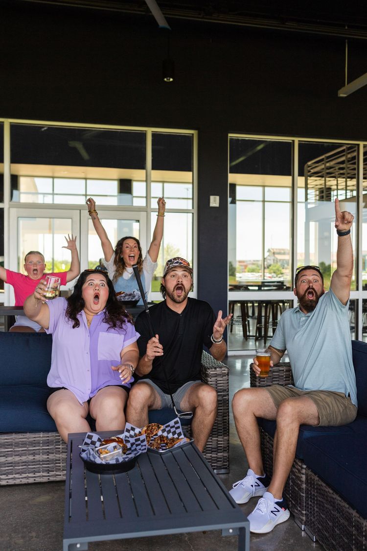 A group of people are sitting on a couch watching a game.