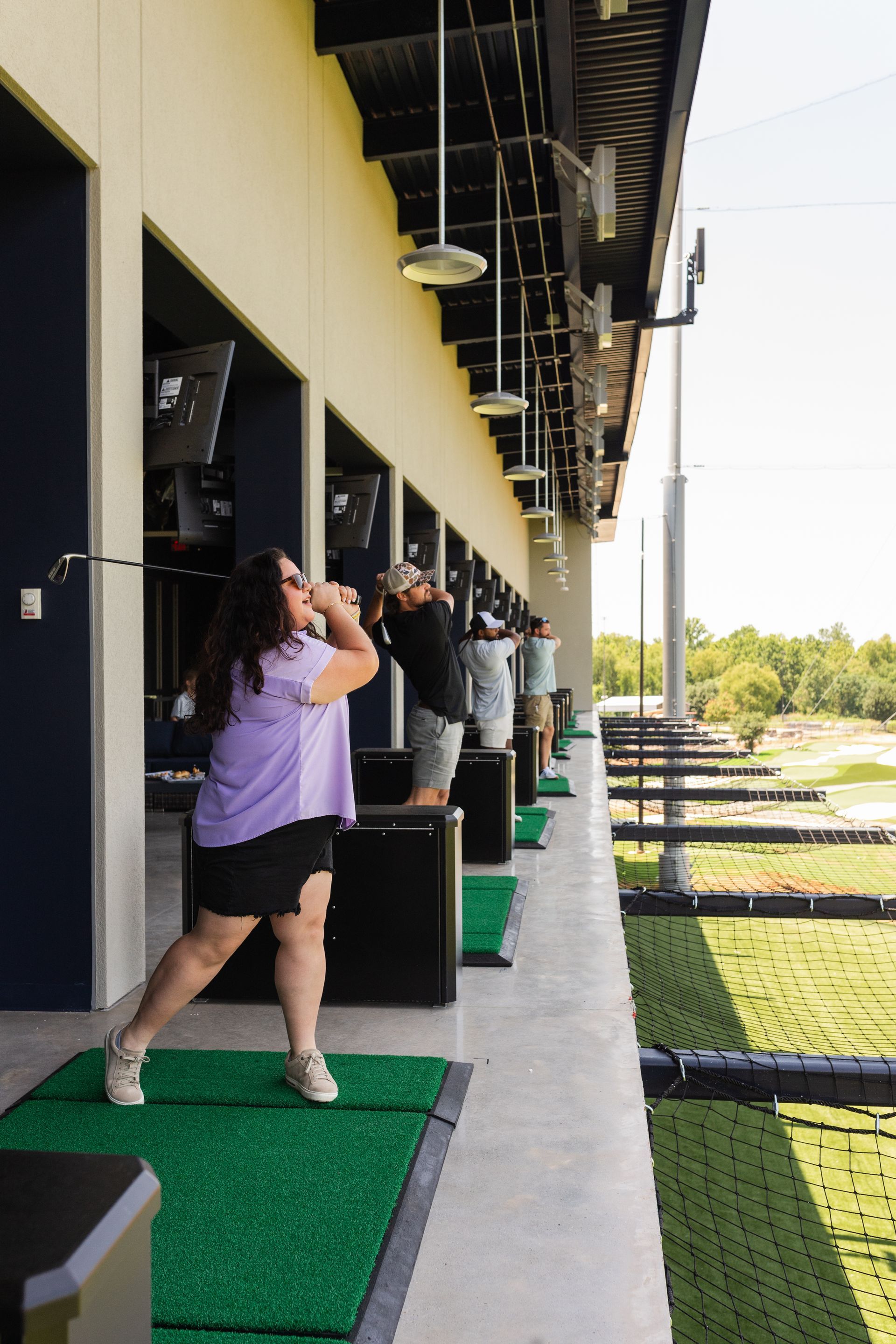 A woman is swinging a golf club at a golf course.