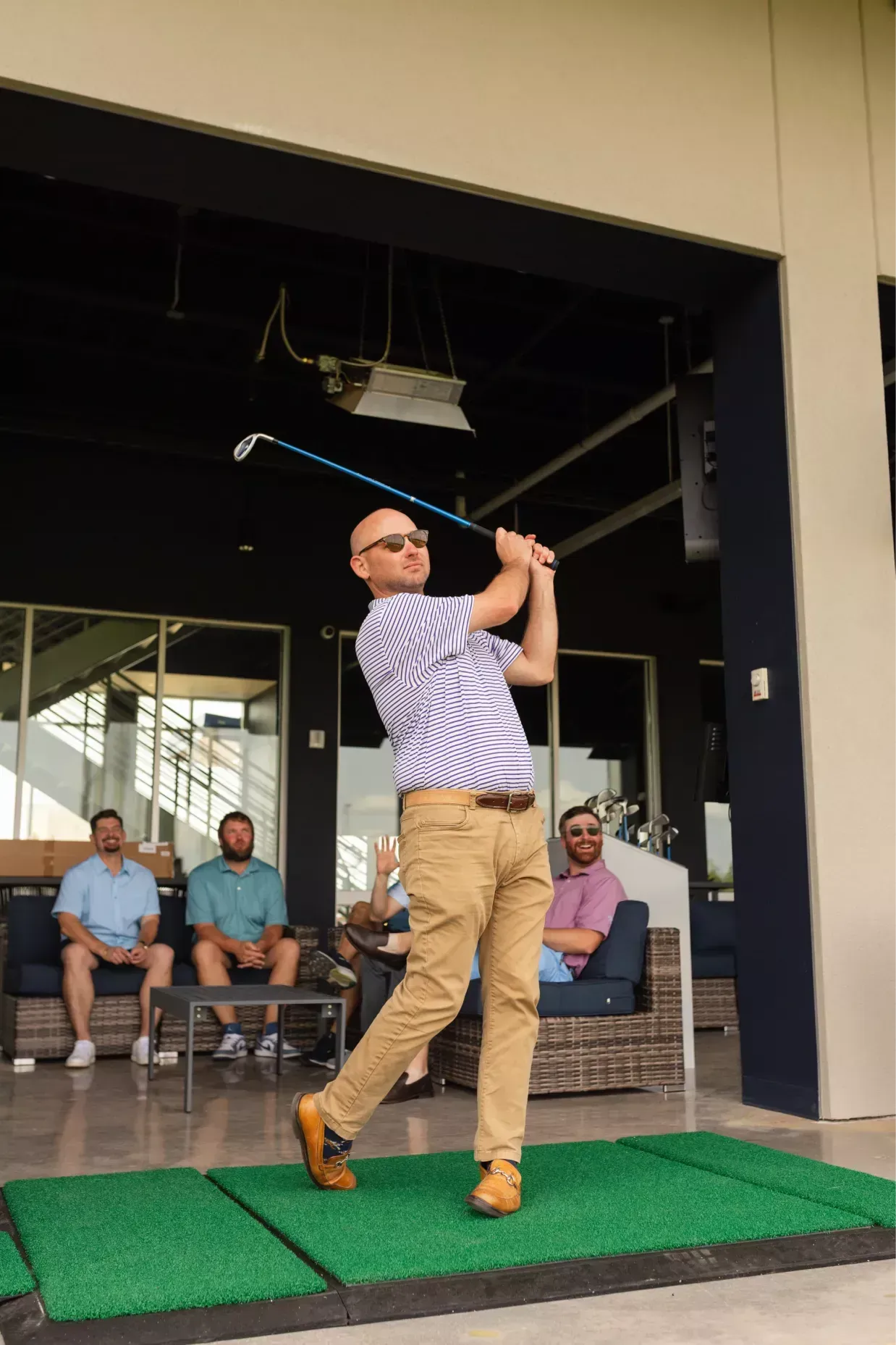 A man is swinging a golf club on a driving range.