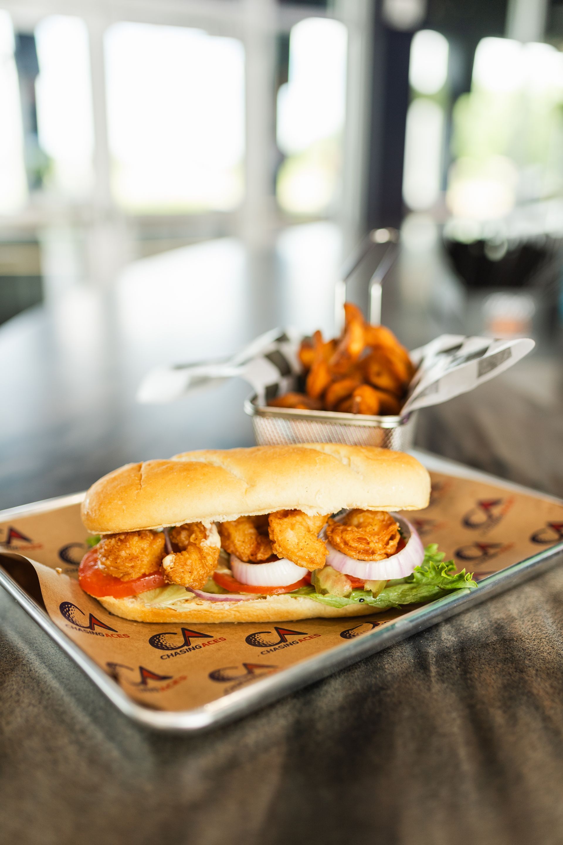 A shrimp sandwich is sitting on a metal tray on a table.