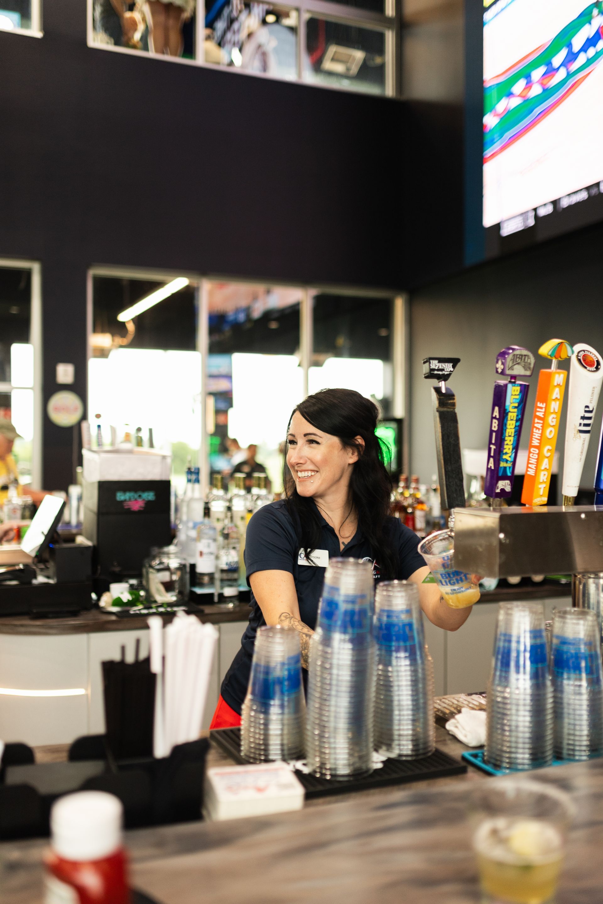 A woman is serving drinks at a bar in a restaurant.