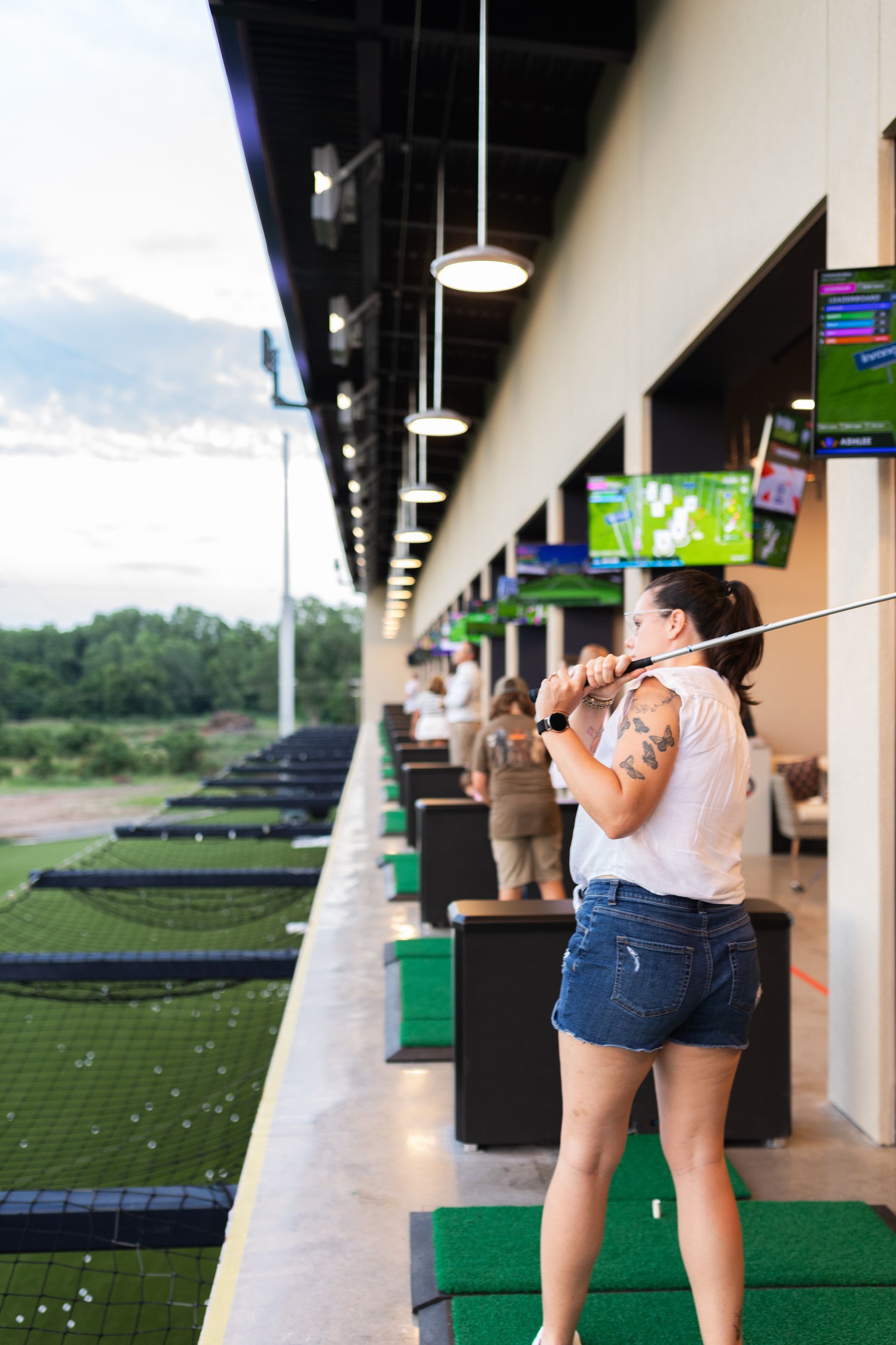 A woman is swinging a golf club at a golf course.