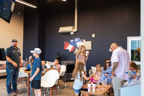 A group of people are standing around tables in a room.