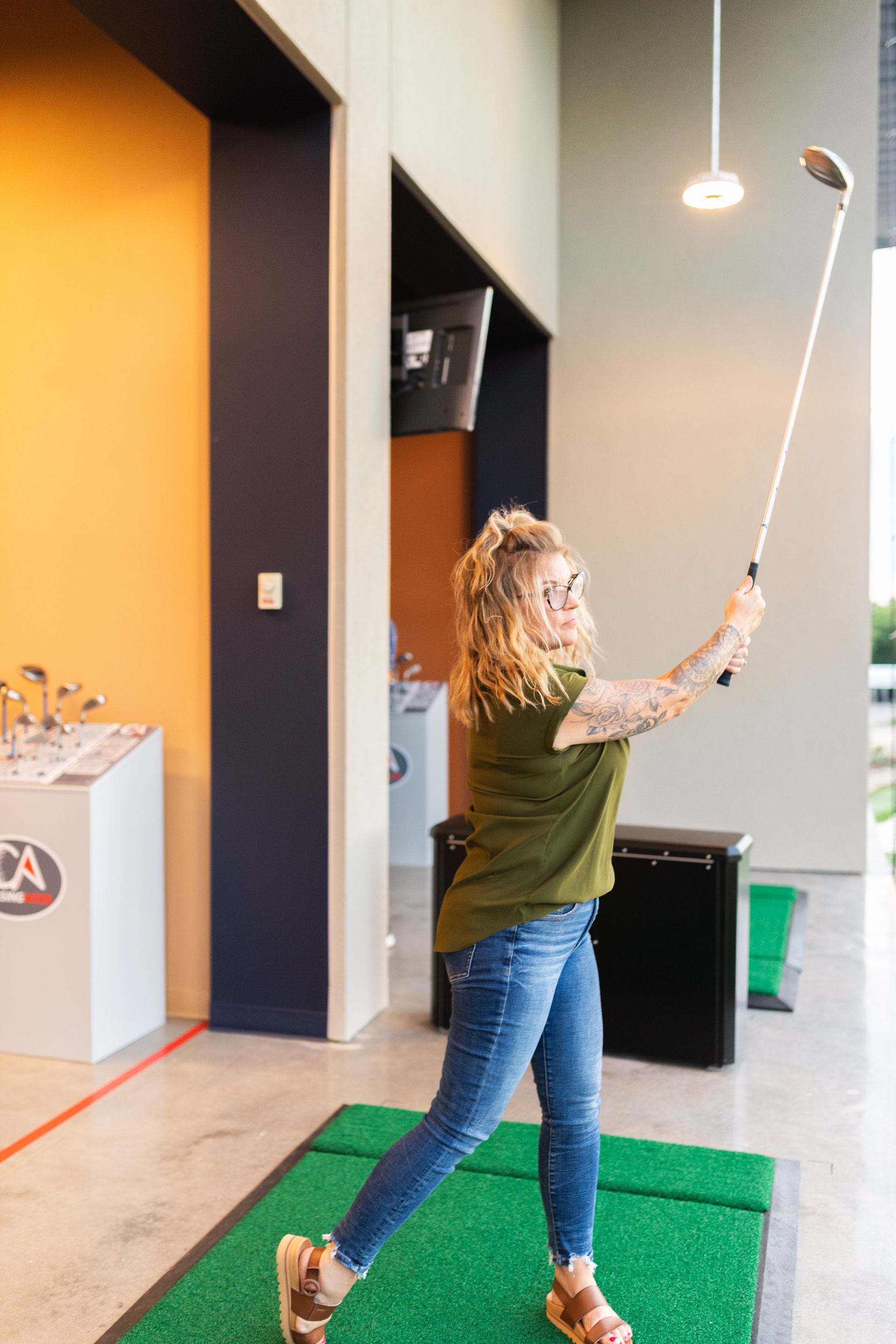 A woman is swinging a golf club on a driving range.
