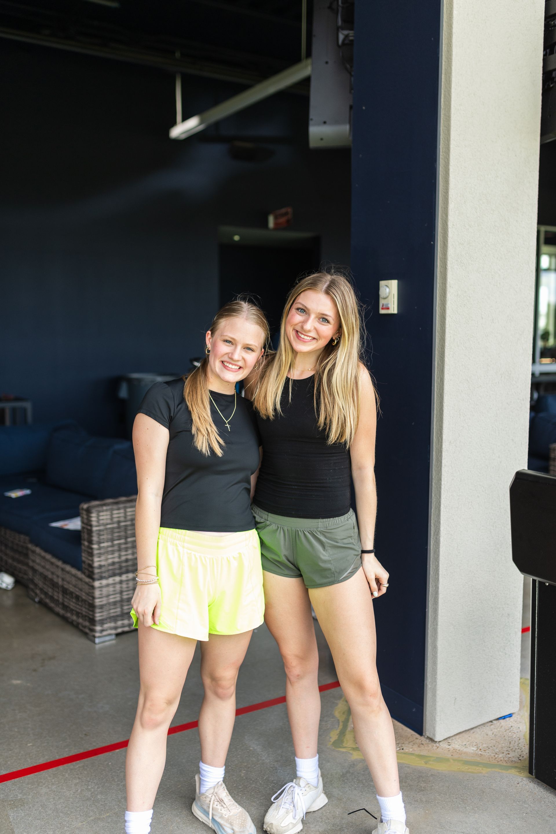 Two young women are standing next to each other in front of a building.