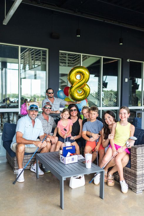 A group of people are sitting around a table with balloons.