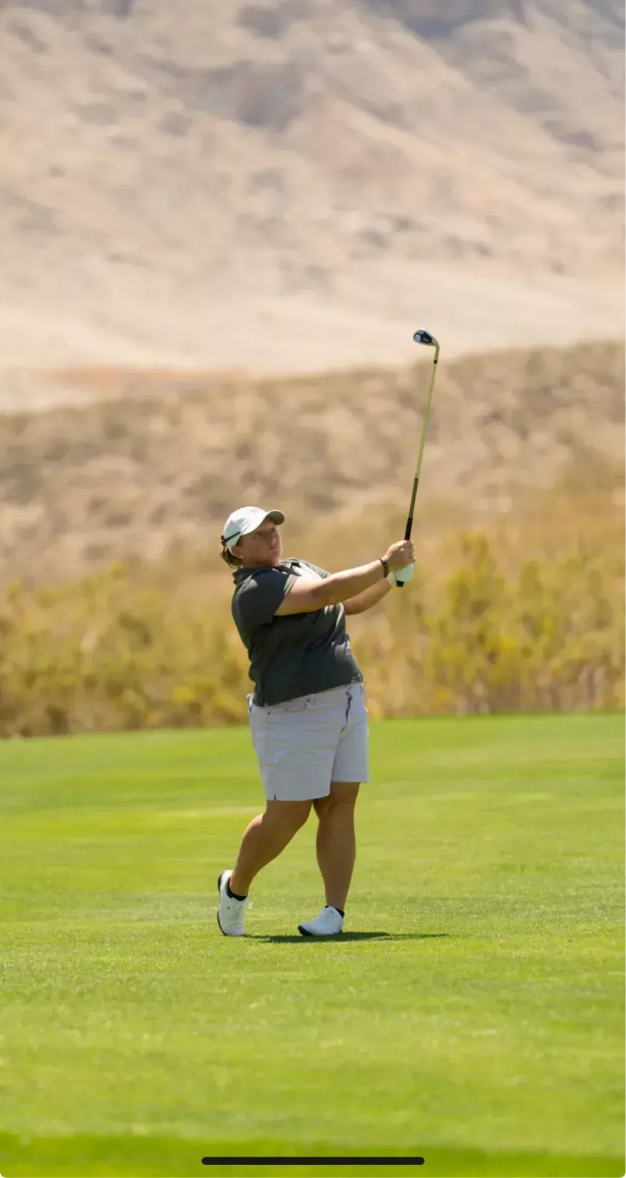 A woman is swinging a golf club on a golf course.