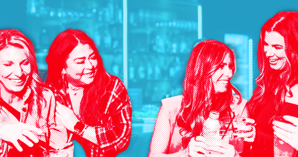 A group of people are standing around tables in a room.