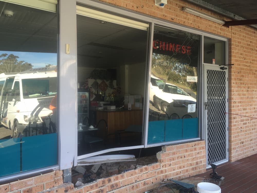 A Brick Building With A Broken Window And A Sign That Says Chinese — South Coast Glass In South Nowra, NSW