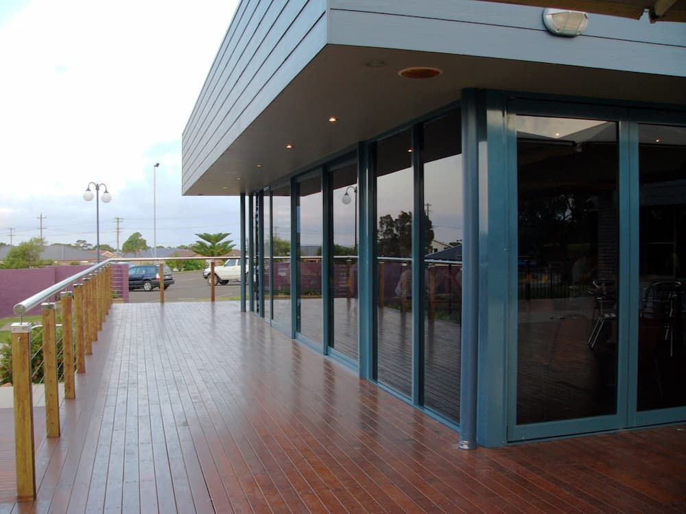 A Large Building With Lots Of Windows And A Wooden Deck — South Coast Glass In South Nowra, NSW