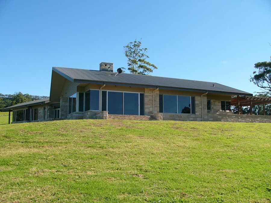 A Large House Sits On Top Of A Grassy Hill — South Coast Glass In South Nowra, NSW
