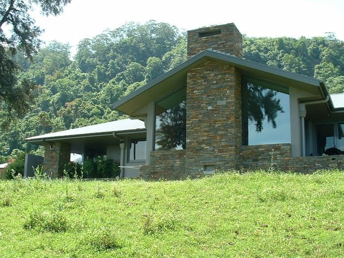 A House Sitting On Top Of A Grassy Hill With Trees In The Background — South Coast Glass In South Nowra, NSW