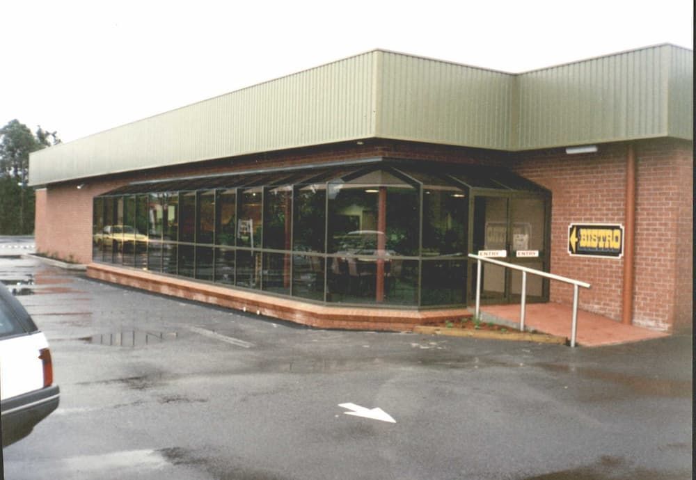 A White Car Is Parked In Front Of A Building That Says Drive In — South Coast Glass In South Nowra, NSW