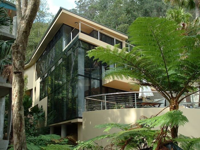 A House With A Lot Of Windows Is Surrounded By Trees — South Coast Glass In South Nowra, NSW