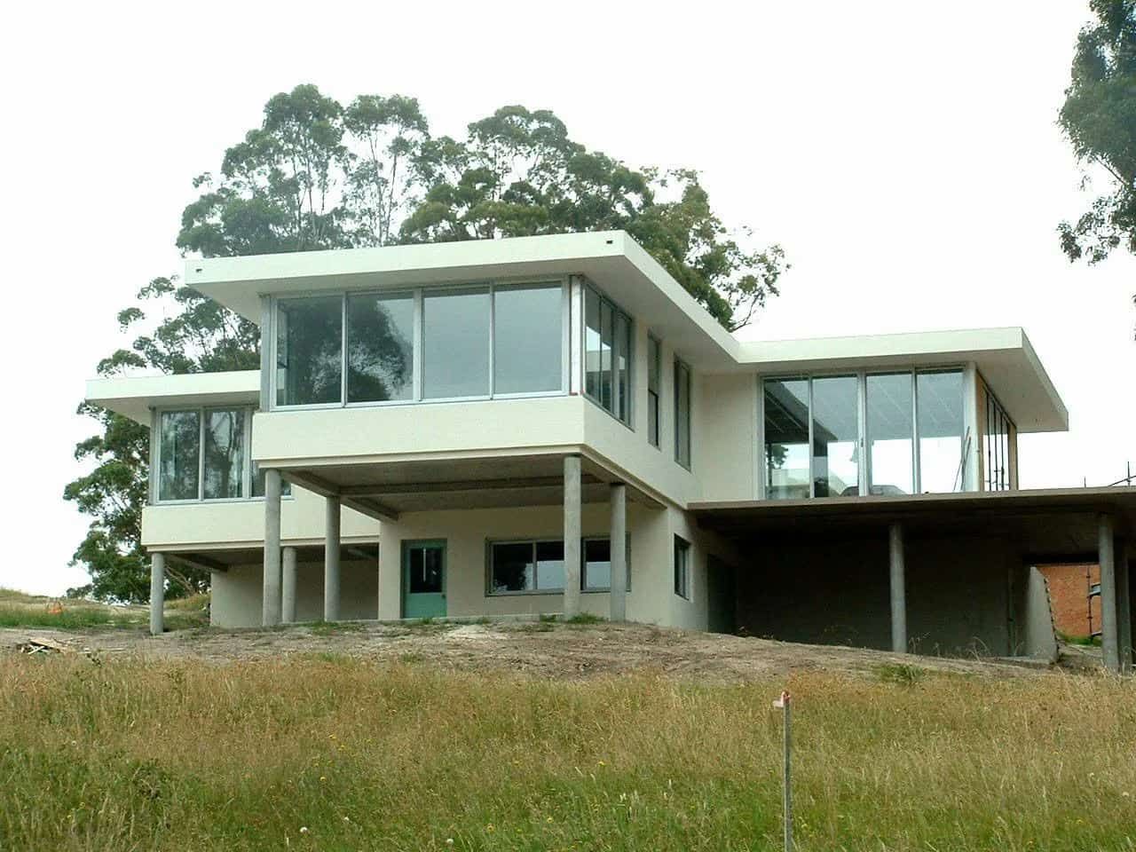 A Large White House With A Lot Of Windows Sits On Top Of A Grassy Hill — South Coast Glass In Sussex Inlet, NSW