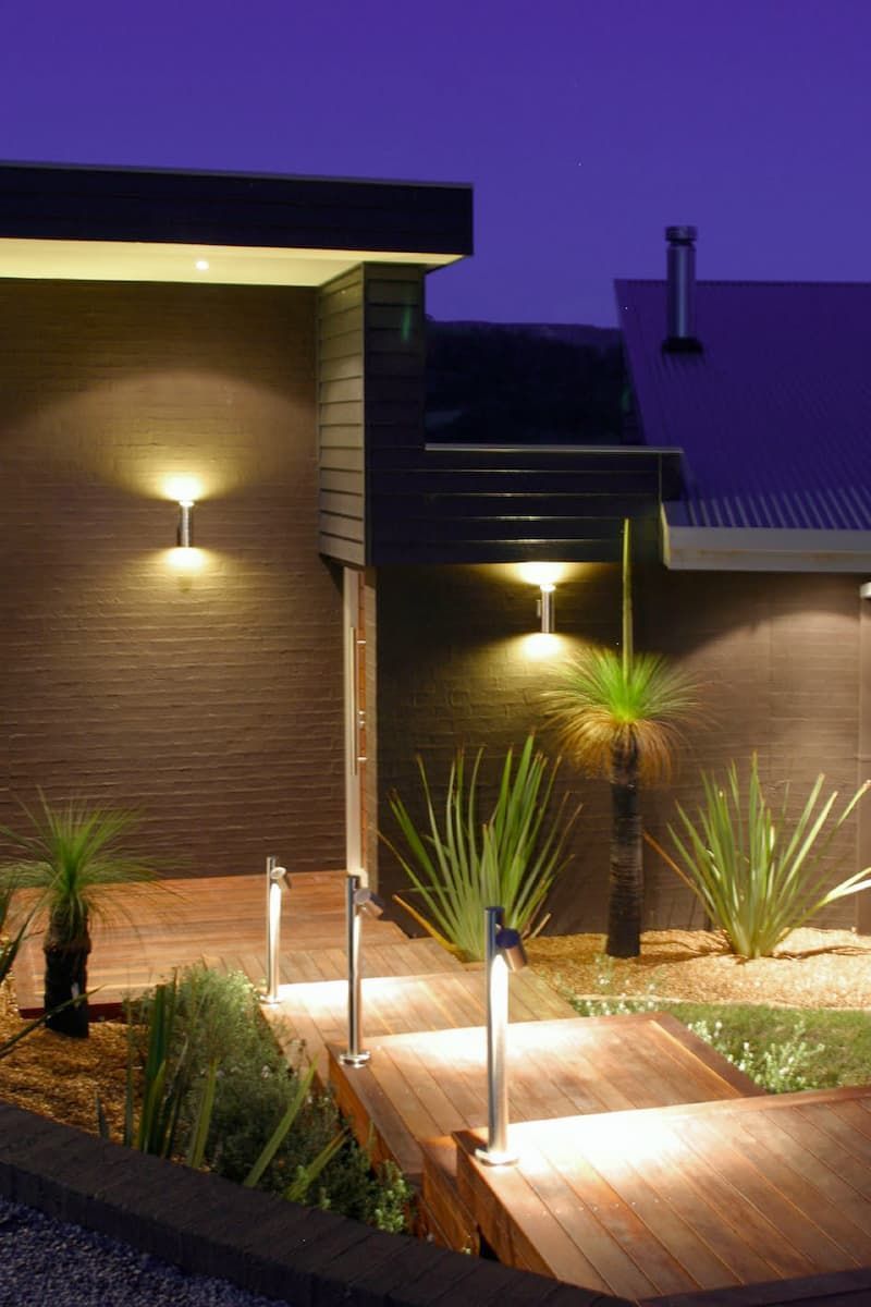 A House With A Wooden Walkway Leading To It Is Lit Up At Night — South Coast Glass In South Nowra, NSW