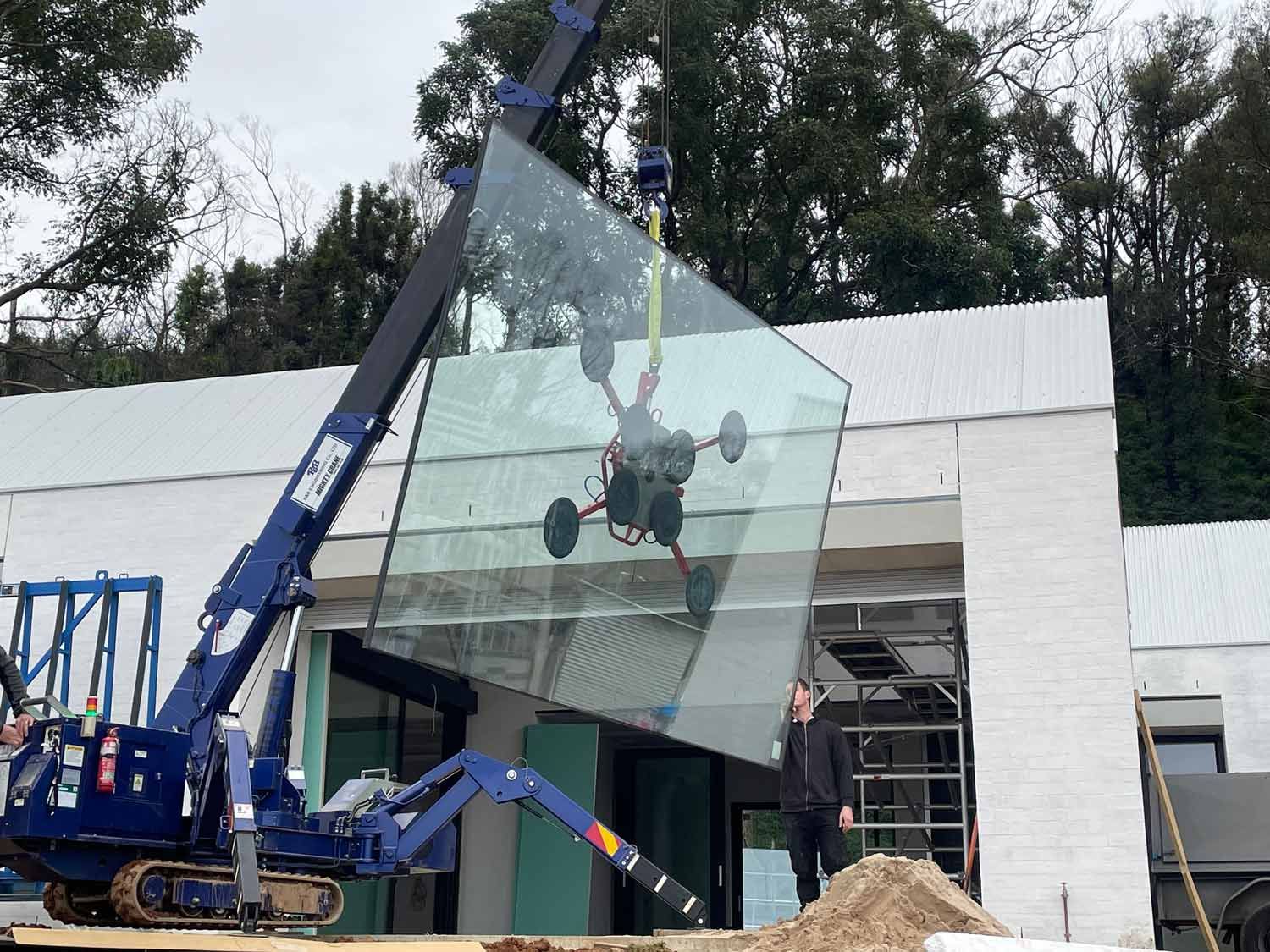 A Blue Crane Installing Glass in a House — South Coast Glass In South Nowra, NSW