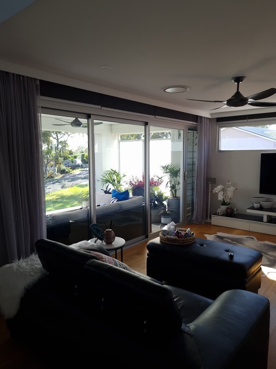 A Living Room With A Couch, Ottoman, And Ceiling Fan — South Coast Glass In South Nowra, NSW