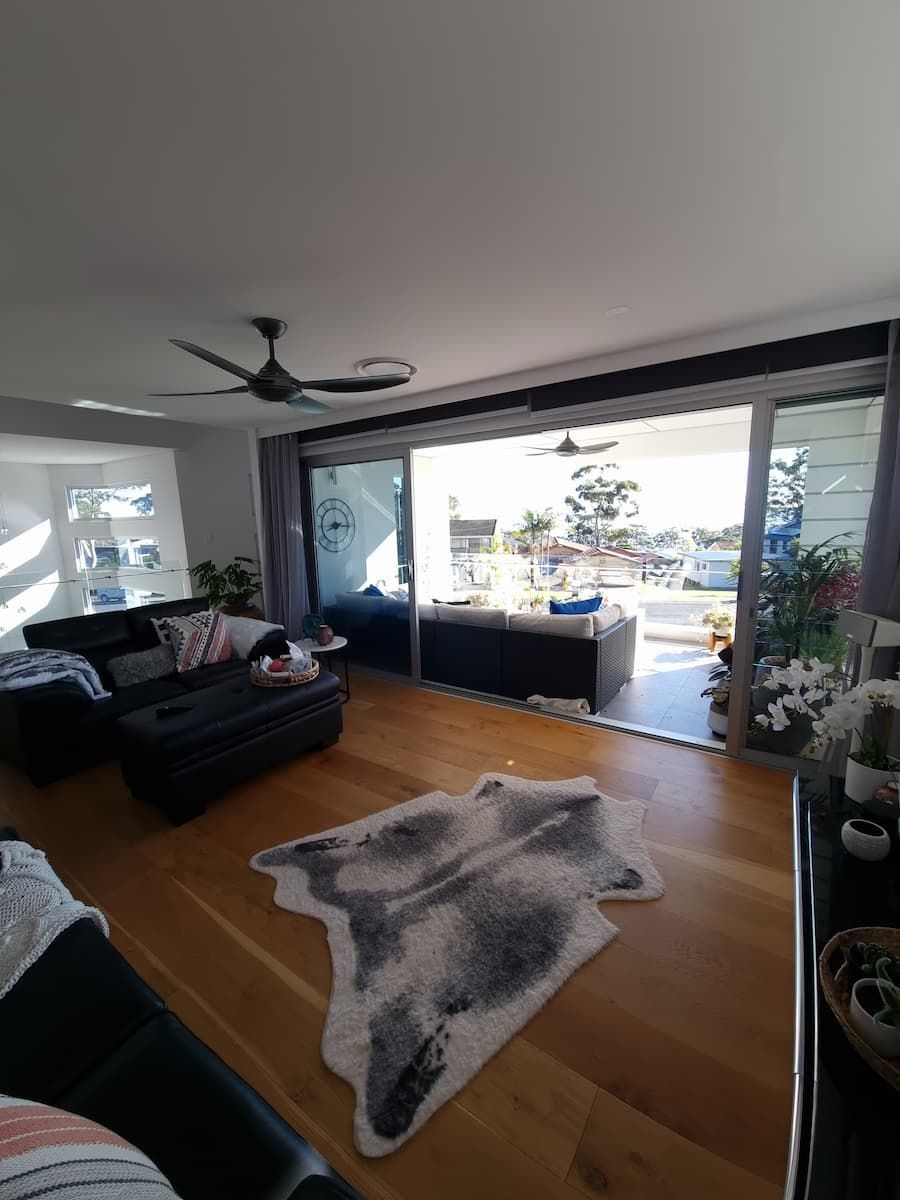 A Living Room With A Rug On The Floor And A Ceiling Fan — South Coast Glass In South Nowra, NSW