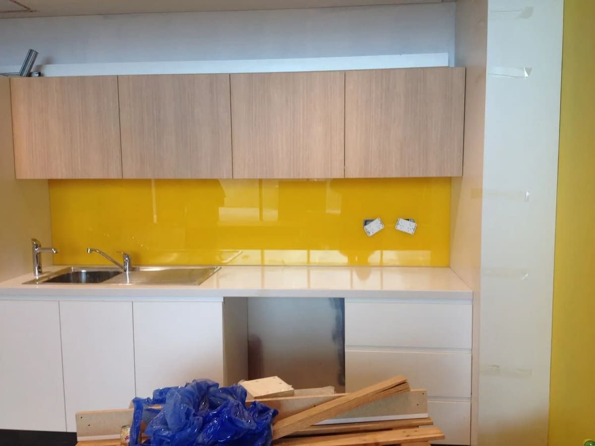 A Kitchen With A Yellow Backsplash And White Cabinets — South Coast Glass In South Nowra, NSW
