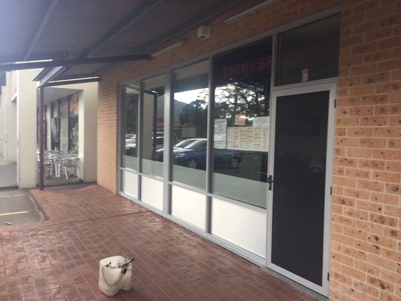 A Dog Is Standing In Front Of A Brick Building — South Coast Glass In South Nowra, NSW