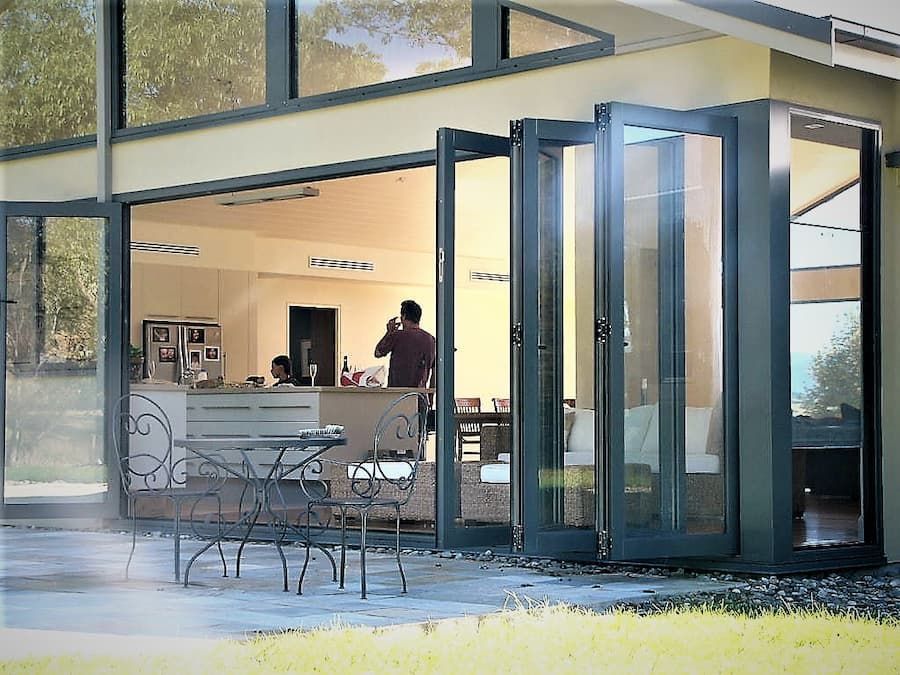 A Man Is Standing Outside Of A House With A Table And Chairs — South Coast Glass In South Nowra, NSW