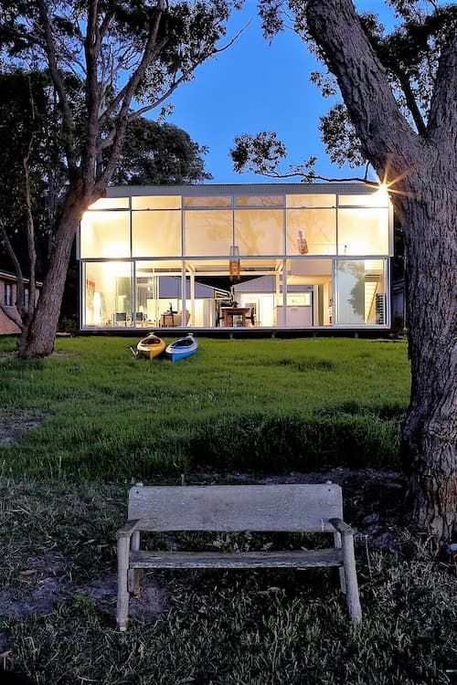 Modern glass house at dusk, with illuminated interior — South Coast Glass In South Nowra, NSW