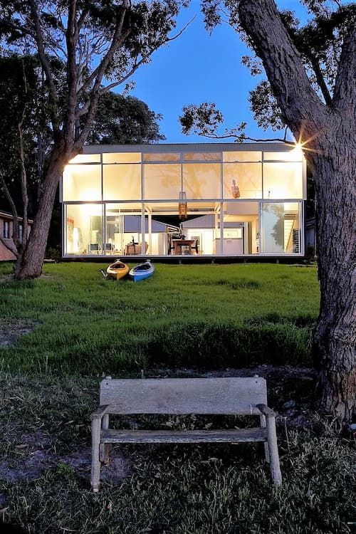 Modern glass house at dusk, with illuminated interior — South Coast Glass In South Nowra, NSW
