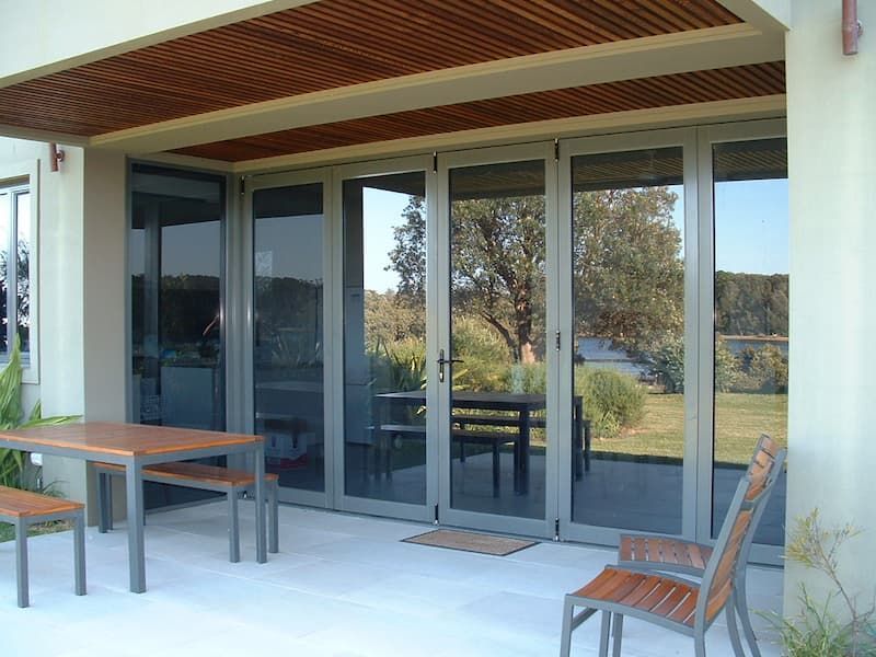 A Patio With A Table And Chairs And Sliding Glass Doors — South Coast Glass In South Nowra, NSW